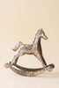 A rustic-style metallic rocking horse figurine with a textured, speckled silver finish, set against a solid, warm beige background.